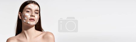 Photo for A young woman with flawless makeup wears a white cream on her face, exuding an air of mystery and elegance. - Royalty Free Image