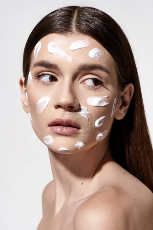 A beautiful young woman with a white cream on her face, exuding a sense of mystery and allure.
