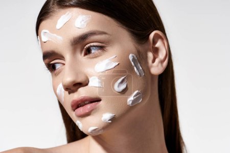 A beautiful young woman sporting a white cream on her face, showcasing a mysterious and alluring look.