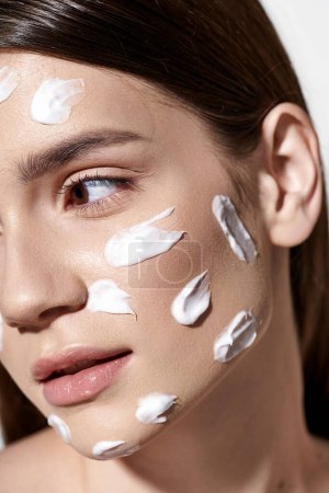 A stunning young woman with a generous amount of white cream gracefully applied on her face, exuding beauty and elegance.