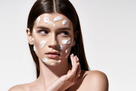 A stunning young woman with an ethereal glow, adorned with a generous amount of white cream on her face.