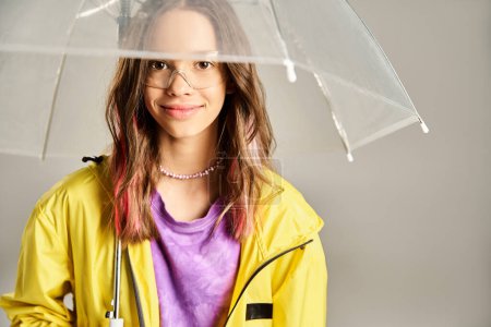 A stylish teenage girl in vibrant attire holds a clear umbrella over her head in an active pose.