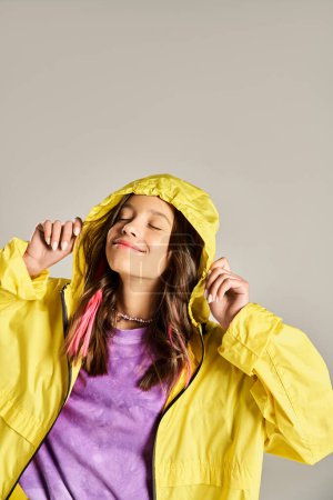 Ein Mädchen im Teenageralter posiert stilvoll in einem gelben Regenmantel für ein Foto.