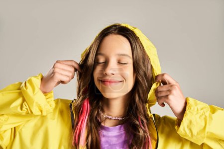 Una adolescente con estilo en un abrigo de lluvia amarillo vibrante posa enérgicamente.