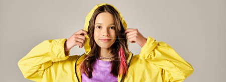 Una adolescente con estilo posa activamente en un impermeable amarillo brillante.
