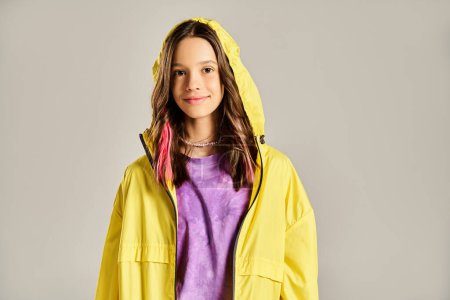 Ein modisches Teenager-Mädchen posiert lebhaft in einem leuchtend gelben Regenmantel, der Energie und Stil ausstrahlt.