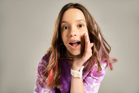 Foto de Una adolescente con estilo y animado golpeando una pose cómica, mano sostenida hacia arriba a la cara en una expresión divertida. - Imagen libre de derechos
