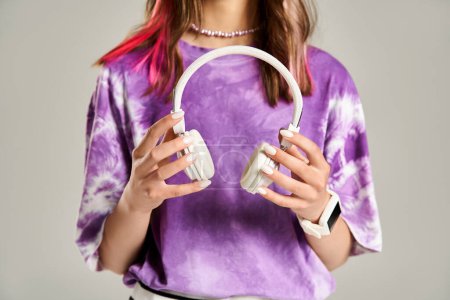 Téléchargez les photos : A stylish teenage girl energetically holds a pair of headphones in her hands. - en image libre de droit