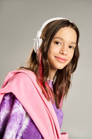 Téléchargez les photos : A stylish teenage girl in a robe enjoys her music through headphones, showcasing vibrant energy and serenity. - en image libre de droit