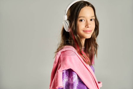 Una adolescente con estilo se ve tranquila con una túnica vibrante, posando activamente mientras usa auriculares.