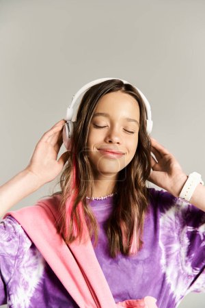 Foto de Una adolescente con estilo en una camisa púrpura está posando activamente mientras usa auriculares. - Imagen libre de derechos