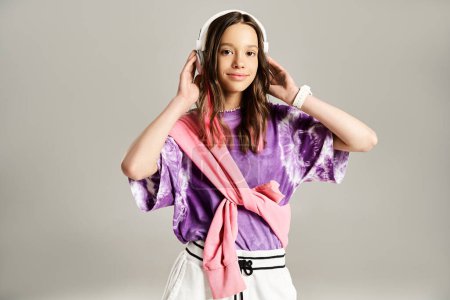 A stylish teenage girl in a vibrant purple shirt wearing headphones, posing actively.