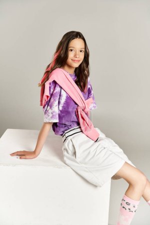 Foto de A stylish, vibrant teenage girl striking a pose while sitting on top of a white box. - Imagen libre de derechos
