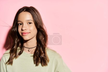 A stylish, vibrant teenage girl poses confidently in front of a pink background.