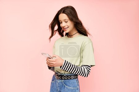 Una chica adolescente con estilo en una vibrante camisa verde enfocada en la pantalla de su teléfono celular.