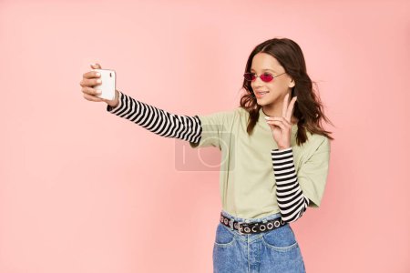 Ein modisches Teenager-Mädchen posiert selbstbewusst und macht ein Selfie mit ihrem Handy.