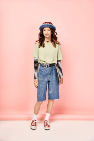 A stylish teenage girl posing actively in a vibrant outfit, wearing a hat and shorts.