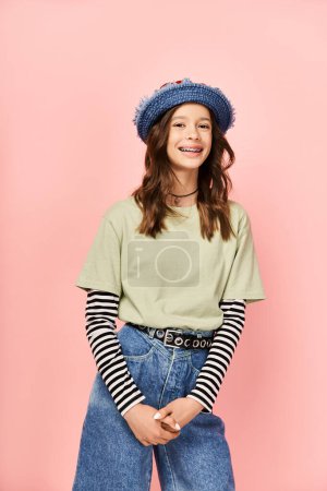 A fashionable teenage girl poses energetically in a blue hat and jeans.