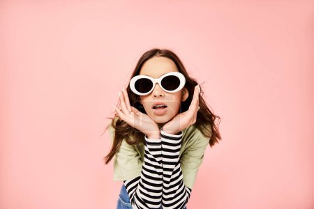 Foto de Una adolescente de moda posa con confianza en una vibrante camisa verde y gafas de sol de moda. - Imagen libre de derechos