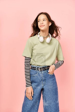 Ein gut aussehendes Teenager-Mädchen posiert aktiv in einem stylischen grünen Hemd und Jeans und präsentiert lebendige Kleidung.