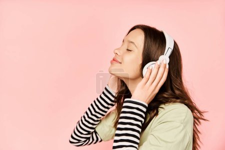 Téléchargez les photos : A fashionable teenage girl in vibrant attire, wearing headphones, immersed in listening to music. - en image libre de droit