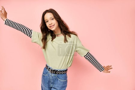 Photo for Stylish teenage girl in a vibrant green shirt joyfully extends her arms in a graceful posing. - Royalty Free Image