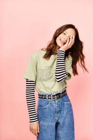 Téléchargez les photos : A stylish teenage girl in a green shirt and jeans energetically posing. - en image libre de droit