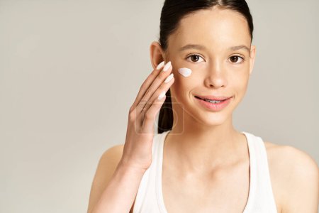 A stylish young woman gracefully applies cream to her face, enhancing her natural beauty and radiance.