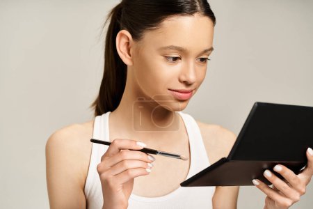 Foto de Una adolescente con estilo sostiene enérgicamente un pincel y una paleta. - Imagen libre de derechos