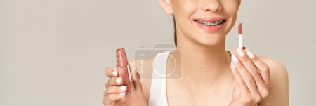 Téléchargez les photos : Une adolescente élégante tenant du rouge à lèvres dans une tenue vibrante, mettant en valeur sa personnalité ludique et active. - en image libre de droit