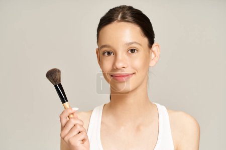 A stylish teenage girl holds a makeup brush in her hand, getting ready to apply makeup.