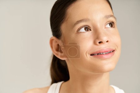 Una adolescente con estilo con aparatos ortopédicos en los dientes mira hacia arriba con una expresión animada, mostrando su traje vibrante.