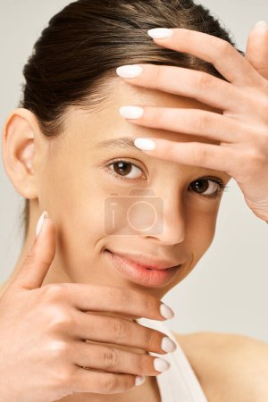 Foto de Una adolescente guapa con un atuendo elegante y vibrante, sosteniendo sus manos en la cara en un gesto expresivo. - Imagen libre de derechos