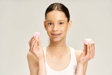 Téléchargez les photos : A stylish teenage girl in vibrant attire gracefully holds cream in her hands. - en image libre de droit