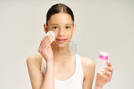 Téléchargez les photos : Une belle adolescente en tenue vibrante tient avec confiance une bouteille de lotion tout en présentant une autre bouteille. - en image libre de droit