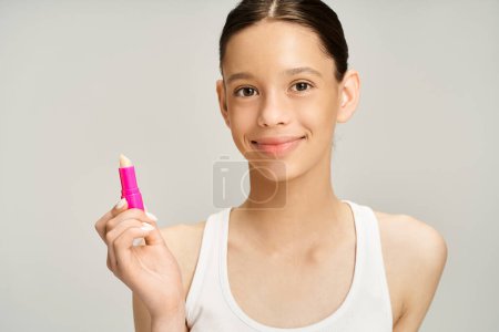 Foto de Elegante adolescente en ropa de moda tiene un lápiz labial rosa en la mano. - Imagen libre de derechos