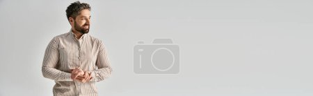 Photo for A stylish man with a beard stands confidently before a pristine white background, exuding charm and allure. - Royalty Free Image