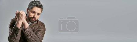 Photo for Stylish man with beard in elegant brown suit posing on a grey studio background. - Royalty Free Image