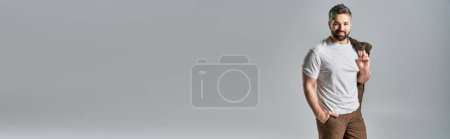 Téléchargez les photos : Un homme barbu pose en tenue élégante sur fond gris dans un décor de studio. - en image libre de droit
