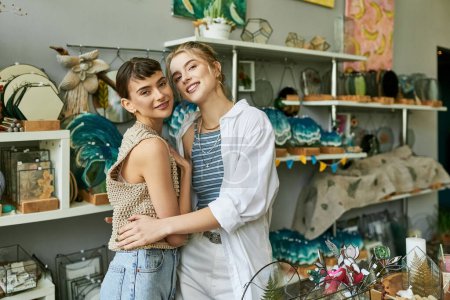Zwei junge Frauen umarmen sich in einem Geschäft liebevoll.