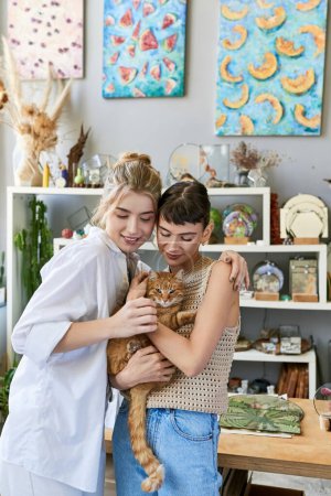 Two women cuddling a cat in a cozy room.