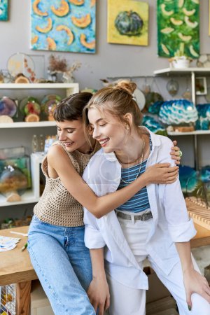 Photo for Two women, a tender and loving lesbian couple, embracing in an art studio. - Royalty Free Image