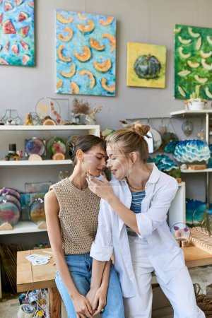 Foto de Dos mujeres, una pareja lesbiana amante, admiran las pinturas en un estudio de arte. - Imagen libre de derechos