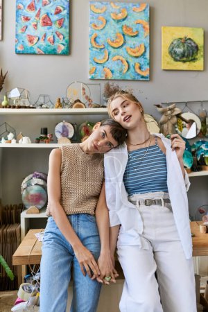 Téléchargez les photos : Un couple de lesbiennes amoureux assis sur un banc dans un studio d'art. - en image libre de droit