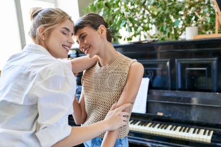 Téléchargez les photos : Deux femmes se tiennent côte à côte, embrassées par la musique du piano. - en image libre de droit