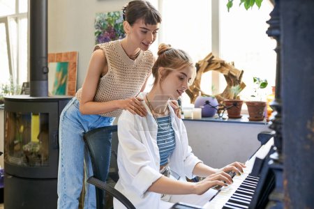 Woman at piano with her girlfriend in art studio.
