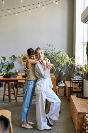 Téléchargez les photos : Deux femmes se tenant côte à côte dans un studio d'art, partageant un moment tendre. - en image libre de droit