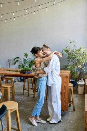 Two women, a loving tender lesbian couple, hugging at an art studio.