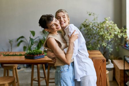 Photo for Two women, an arty lesbian couple, standing close in an art studio. - Royalty Free Image
