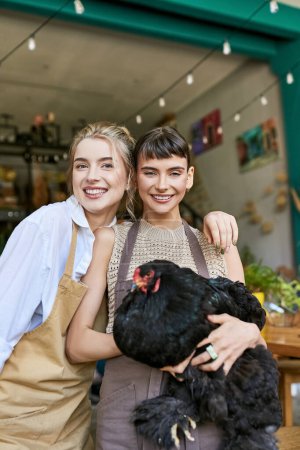 Zwei Frauen halten ein Huhn vor einem Geschäft.